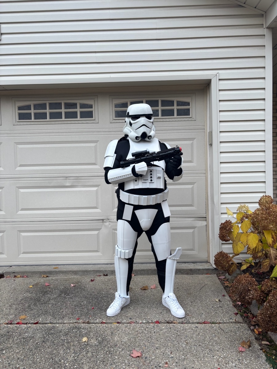 Jorden in a full suit of 3D-printed Stormtrooper armor holding an E11 blaster, standing in a driveway.